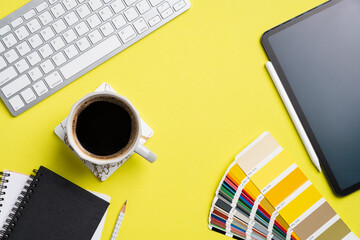 Fototapete - Designer desk top view with computer keyboard, graphic tablet color palette, notebook, cup of coffee on yellow background. Flat lay, view from above. Creative professional workspace.