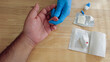 © Grandbrothers - A medical personnel wearing gloves is performing a finger prick blood draw before a diagnostic testing at a doctors office. Used lancet and blood contaminated gauze pad is on the table