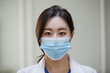 © stciel - 마스크를 쓰고 하얀색 가운을 입은 여성 의사