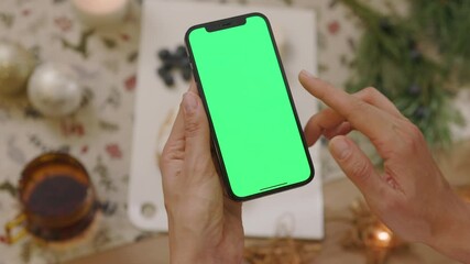 Top view close up hands woman hold phone with vertical green screen. Background tasty dessert. Christmas time. Blogger blogging cuisine dish. Slow motion