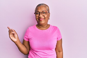 Poster - Senior african american woman wearing casual clothes and glasses smiling happy pointing with hand and finger to the side