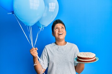 Poster - Teenager hispanic boy celebrating birthday with cake holding balloons angry and mad screaming frustrated and furious, shouting with anger looking up.