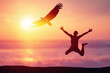 Happy man jumping at tropical beach with eagle bird flying on sunset sky abstract background.
