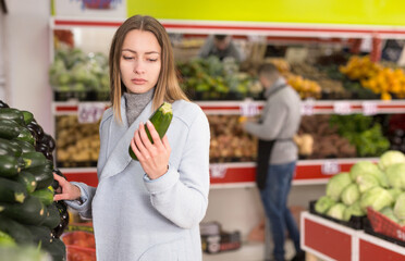 Female shopper picks cucumbers at grocery store. High quality photo