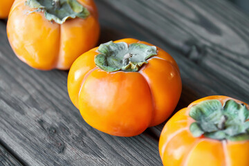 Ripe fresh persimmon on brown wooden rustic background. Close-up, selective focus