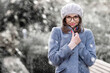 Happy young woman standing outside and getting cold while snowing. Portrait shot of attractive woman wearing hat and winter coat while enjoy falling snow.