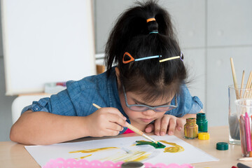 Portrait of young Asian disabled child down's syndrome girl draw a picture with watercolor in element classroom