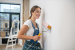 © zinkevych - Young woman with paint roller in her hand painting wall