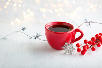 Sticker - Red cup of coffee,  Christmas decoration and lights of garland   on white  rustic wooden  table.  Selective focus.