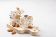 Torrone - soft italian nougat with almonds. On small wood board. White background. Copy space.