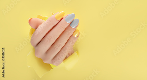 Foto Female hand with yellow nail design
