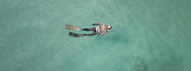 Wall Mural - Aerial drone top down ultra wide panoramic photo of spearfishing scuba diver in tropical exotic shallow bay with turquoise clear waters