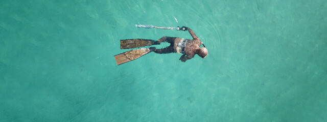 Wall Mural - Aerial drone top down ultra wide panoramic photo of spearfishing scuba diver in tropical exotic shallow bay with turquoise clear waters