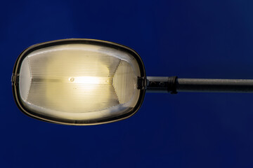 The Street lamp shining against dark blue sky.