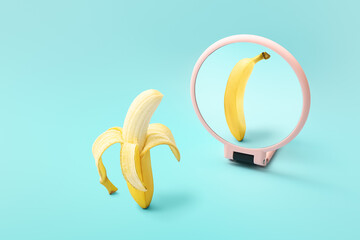 Wall Mural - Banana looking at its reflection in mirror on color background