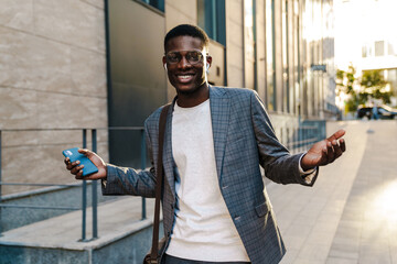 Wall Mural - Attractive young african businessman in wireless earphones