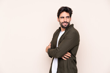 Wall Mural - Young handsome man with beard over isolated background with arms crossed and happy