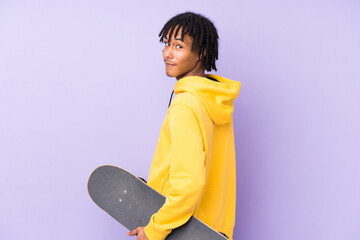 Wall Mural - Young african american man isolated on purple background with a skate