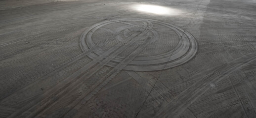 Dirty concrete grey floor in industrial warehouse building. Round tire tracks of truck.