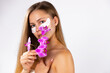 © Viorel - Portrait of a beautiful girl with eye patches, holding a twig of pink orchid. White background. Space for business card