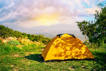 Wall Mural - orange tent on hill with mountains in background at sunrise