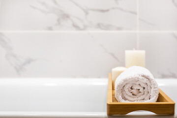 Close up view of marble white bathroom accessories, white towels, candles and copy space