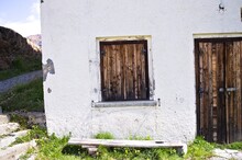 An Abandoned White Building With Wooden Doors And Wooden Shutters In The Italian Alps (Trentino, Italy, Europe)