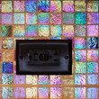 © Mint Images - Black plug socket in colourful mosaic tile.