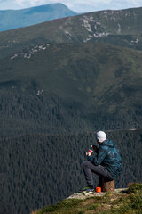 man sitting on the stump eating hiking food looking on mountains