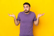 © luismolinero - Young caucasian handsome man isolated on yellow background having doubts while raising hands