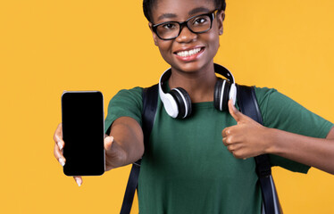 Aufkleber - Black Female Student Showing Smartphone Screen Gesturing Thumbs-Up, Yellow Background