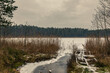 Zimowy widok na zniszczony pomost nad zamarzniętym jeziorem