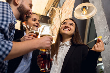 Wall Mural - Laughting. Happy co-workers celebrating corporate event after tensioned work day. Look delighted, friendly, cheerful. Drinking beer. Concept of office culture, teamwork, friendship, holidays, weekend.