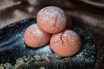 homemade delicious pink cookies pulled over black natural stone presentation area