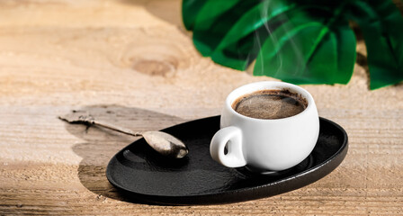 Cup of espresso on a wooden rustic table, steam rises above the coffee. Minimalistic style. Close-up with copy space