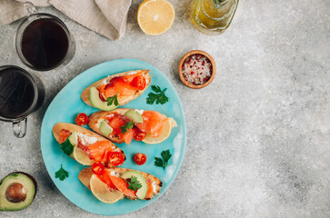 Wall Mural - Smoked salmon sandwich with cream cheese, lemon, avoado and tomato on gray background.