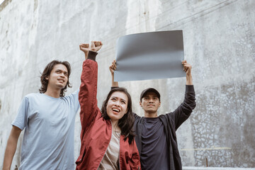 Portrait students holding blank paper who are burning with enthusiasm doing a demonstration together