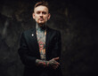 © Fxquadro - Portrait of a hipster person with tattooed body dressed in luxurious black jacket poses in dark background looking at camera with serious face.