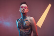 © Fxquadro - Caucasian bearded and tattooed macho with modern haistyle and naked torso poses in colourful background with lights.