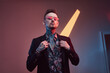 © Fxquadro - Well dressed tattooed hipster person with sunglasses and modern hairstyle poses in dark room with colourful walls and lights.