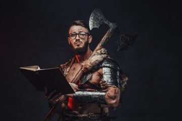 Sad nordic warrior in light armour with fur with eyeglasses and book holding huge axe on his shoulder in dark background.