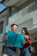 © Odua Images - husband and wife holding a land certificate with a new home background