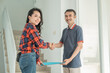 © Odua Images - smilling asian male housing developer handing home certificate to asian woman while shaking hands in the house