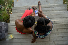 Overhead View Of Sisters Using Phone On Front Porch Steps
