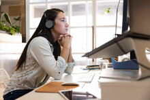 Owner Of Startup Business Wearing Headphones At Computer