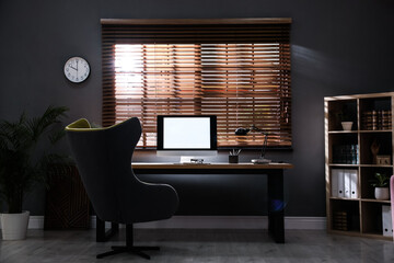 Stylish room interior with modern computer and comfortable office chair