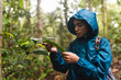 © KIKE ARNAIZ/Stocksy - Girl in blue raincoat watching a plant