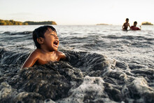 Portrait Of A Panamanian Kid Playing Alone At The Beach With The Waves