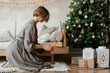 © Alina Hvostikova/Stocksy - Woman putting presents under Christmas tree