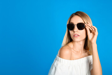 Poster - Beautiful woman in stylish sunglasses on light blue background, space for text